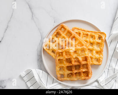 Perfekte herzhaften keto Waffeln. Zwei Zutaten chaffles auf die Platte über der weißen Marmor Hintergrund. Eier und Parmesan low carb Waffeln. Top View oder flach. Kopieren Sie Platz für Text oder Design. Stockfoto