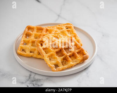 Perfekte herzhaften keto Waffeln. Zwei Zutaten chaffles auf die Platte über der weißen Marmor Hintergrund. Eier und Parmesan low carb Waffeln. Stockfoto