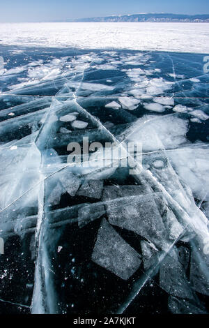 Transparente dunkles Eis am Baikalsee mit gefrorenen Eis und schönen großen Risse. In der Ferne ist auf Eis und Schnee Berge am Horizont. Stockfoto