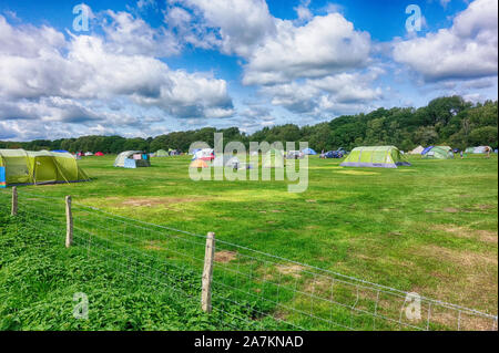 Norden, England - 29.August 2018: Bunte Zelte auf einem grünen Feld Campingplatz unter blauen bewölkten Himmel, mit Campingplatz und ihr Zelt Stockfoto