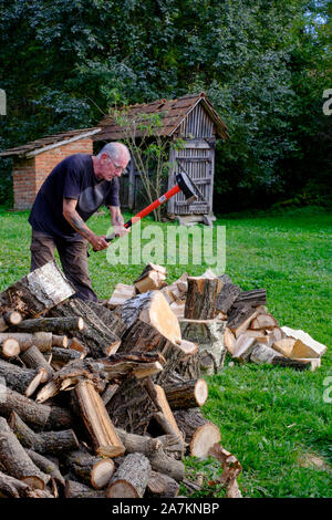 Man verwendet eine Aufspaltung in Garten maul Protokolle für Kraftstoff in der Vorbereitung für die kommende Wintersaison zala Ungarn Stockfoto