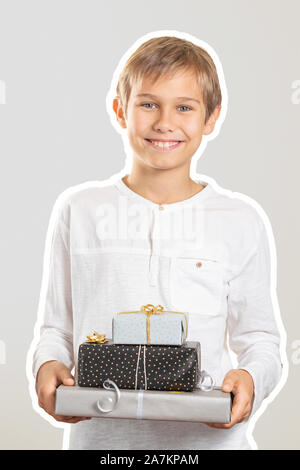 Happy Boy holding Stapel Papier eingewickelt vorhanden Geschenkboxen. Zeitschrift collage Stil mit hellen Grau Farbe Hintergrund. Feiertage, Weihnachten Konzept Stockfoto