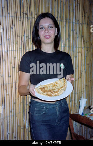 Junge lokale weibliche Bedienung einer lokalen Pfannkuchen auf einer Platte in ein kleines Restaurant, das in Catania Sizilien 1990 s Stockfoto