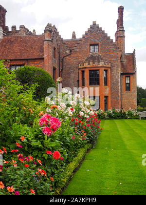 Chenies Manor House mit Blick auf South West, die durch die Grenzen mit bunten Pink Dahlia Sorten verpackt gerahmt und Rose Bush auf eine September Abend. Stockfoto