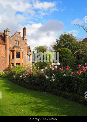 Chenies Manor House mit Blick auf South West, die durch die Grenzen mit bunten Pink Dahlia Sorten und Kosmos auf eine feine September Abend umrahmt. Stockfoto