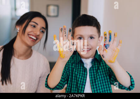 Niedlicher Junge zeigt seine Hände in hellen Farben gemalt Stockfoto