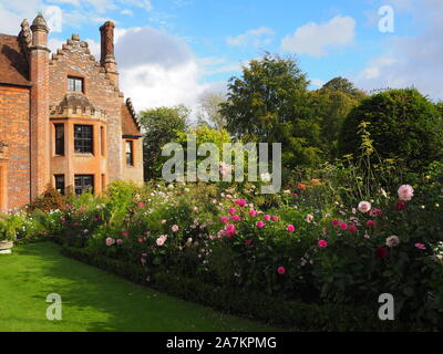 Chenies Manor House mit Blick auf South West, die durch die Grenzen mit bunten Pink Dahlia Sorten und Kosmos auf eine feine September Abend umrahmt. Stockfoto