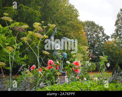 Chenies Manor Garden am Ende des Sommers. Jonathan Hateley Skulptur unter den Fennels seedheads, Dahlie 'Labyrinth', und Stockrosen mit hohen Bäumen. Stockfoto