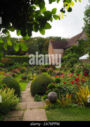 Blick durch das Schlüsselloch Akebia Rebe zur versunkenen Garten Chenies Manor an Dahlia Zeit. Weg zu den terrassenförmig angelegten Garten und Pavillon. Stockfoto