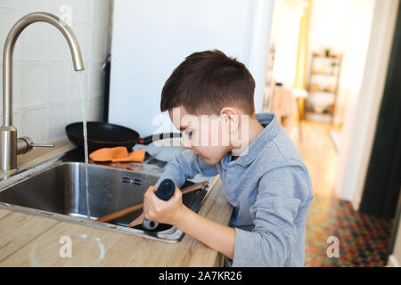 Kleiner Junge Geschirr in der Küche zu Hause waschen Stockfoto