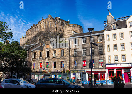 Blick auf die Burg von Edinburgh über historische Gebäude in der Grassmarket mit blauem Himmel. Edinburgh, Schottland. Stockfoto