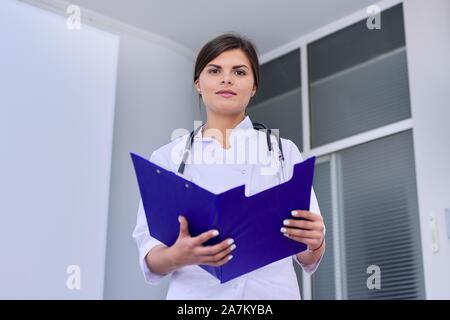 Frau Doktor mit Stethoskop lesen medizinische Dokumente in Ordner der Zwischenablage Stockfoto