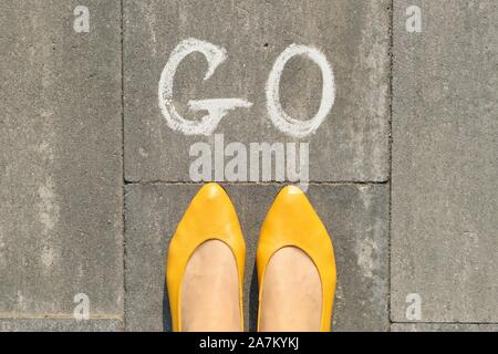 Wort gehen auf grau Bürgersteig mit Frauen Beine geschrieben, Ansicht von oben Stockfoto