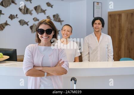 Lächelnde Frau Gast in der Nähe der Rezeption, freundlich Mann und Frau hotel Arbeitnehmer Stockfoto