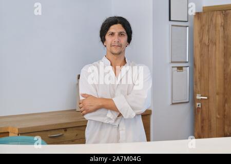 Männliche hotel Arbeitnehmer mit Blick auf die Kamera mit gekreuzten Armen Stockfoto