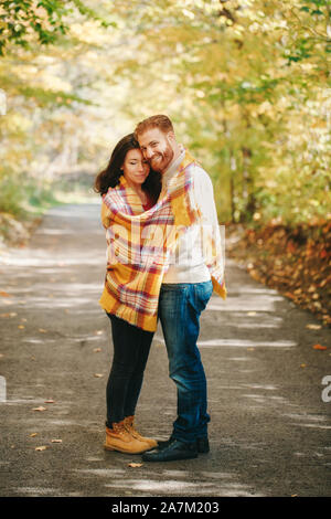 Schönes Paar Mann Frau in der Liebe. Freund und Freundin eingewickelt in gelb Decke umarmen ständigen Outdoor im Park auf Herbst Tag. Togetherne Stockfoto