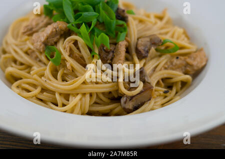 Cremige Spaghetti mit Huhn und gemischte Pilze. Mit Frühlingszwiebeln bestreut in Ringe schneiden. Frisch zubereitet und als gesunde und schnelle Mahlzeit serviert. Stockfoto