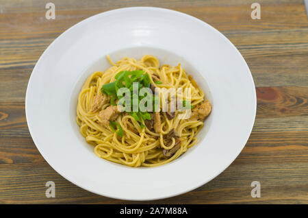 Cremige Spaghetti mit Huhn und gemischte Pilze. Mit Frühlingszwiebeln bestreut in Ringe schneiden. Frisch zubereitet und als gesunde und schnelle Mahlzeit serviert. Stockfoto