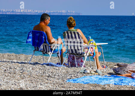 Paar auf Liegestühlen am Strand von Konyaalti, Antalya, Türkei Urlaub, Türkei, Türkische Riviera, Mittelmeer, Stockfoto