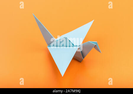 Origami Vogel auf dunklen gelben Hintergrund. Japanische gefaltetes Papier Schwan. Frieden und Hoffnung Symbol Stockfoto