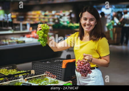 Frau kauft Trauben in Store Stockfoto