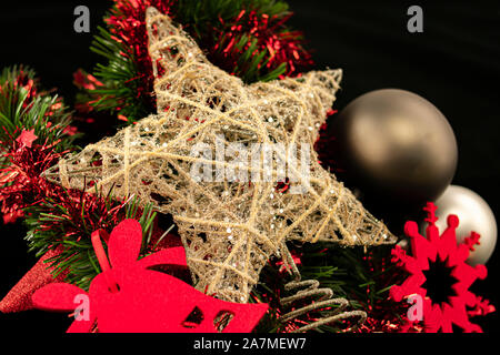 Star Zusammensetzung zusammen liegen mit Schneeflocke und Glockensymbol in rotem Filz mit grauen Kugeln und grüne und rote Lametta Bett, mit hellen Elementen auf Schwarz Stockfoto