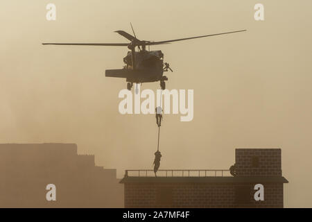 Militärischen Kampf und Krieg mit dem Hubschrauber in das Chaos und Zerstörung zu fliegen. Soldaten aus Seil auf den Boden von Chopper aussetzen. Militärisches Konzept Stockfoto