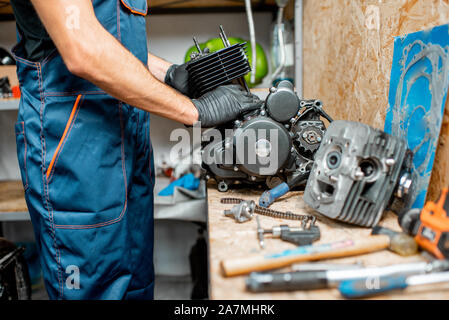 Arbeiter zerlegen Motorrad Motor während einer Reparatur an den Arbeitstisch des Workshops, close-up mit kein Gesicht Stockfoto