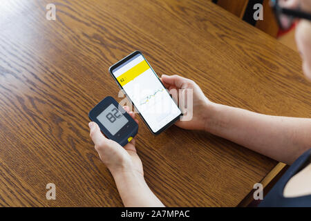 Frau vergleich Ergebnis der Glukose überprüfen Sie die traditionellen glucometer und auf dem Handy lesen von moderner Technologie remote Sensor Stockfoto