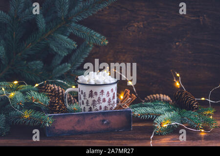 Tanne farbige Keramik Becher mit Kaffee oder heiße Schokolade mit Marshmallows auf hellen Hintergrund mit glitzernden Girlande Stockfoto