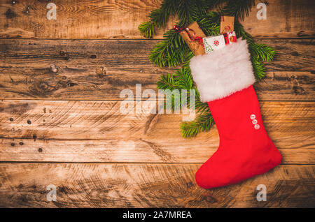 Weihnachten Rote Socke mit weißem Pelz und Geschenke auf einer hölzernen rustikalen Hintergrund. Flach oder Draufsicht Bild mit kopieren. Stockfoto
