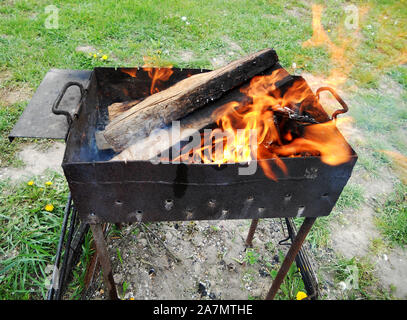 Schöne rote Feuer von Schicht Holz, dunkel grau schwarz Kohlen in Metall brazier. Holz Brennen in der brazier auf helle gelbe Feuer. Flammen Brände prepar Stockfoto