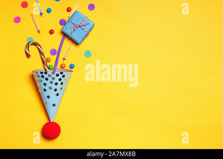 Geburtstag gelber Hintergrund mit Party caps Geschenke Konfetti candy Kerzen für einen Kuchen mit der Kopie. Stockfoto