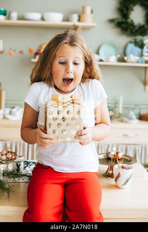 Süße kleine Mädchen mit Weihnachtsgeschenk zu Hause Stockfoto