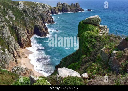 Mit Blick auf den einsamen Strand westlich von Logan Rock in der Nähe von Porthcurno, Cornwall, von der Küste weg. Die einsame Figur betont die Einsamkeit. Stockfoto