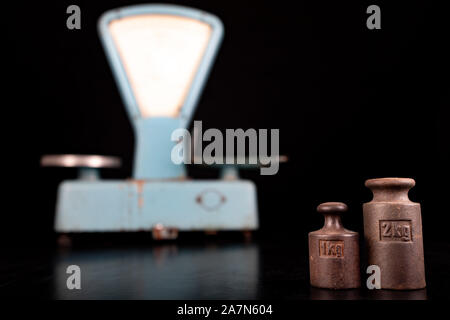 Das alte Gewicht Rohstoffe aus der kommunistischen Ära zu wiegen. Shop Zubehör auf einem gestohlenen Tabelle. Der dunkle Hintergrund. Stockfoto
