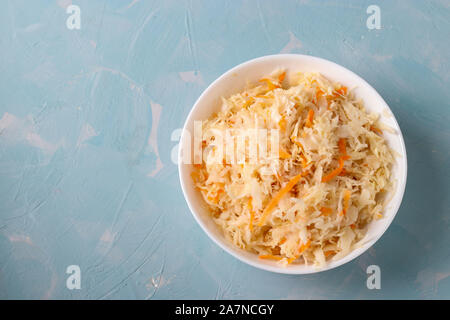 Hausgemachten Sauerkraut mit Karotten in einer Schüssel auf einem hellblauen Hintergrund, fermentierte Lebensmittel, Ansicht von oben Stockfoto