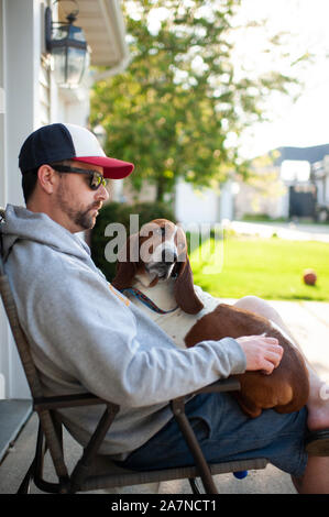 Mann 30-40 Jahre alt im Stuhl mit Basset Hound Dog auf seinem Schoß sitzen Stockfoto