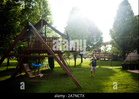 Mädchen Schwingen hoch auf den Kopf, während Bruder Uhren zu Hause besorgt Stockfoto