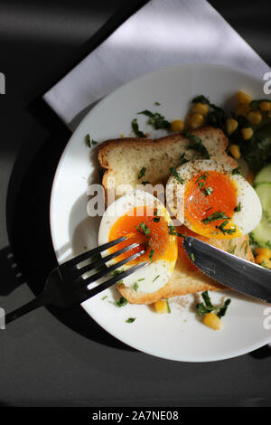 Gesundes Frühstückskonzept. Pochiertes Ei mit Flüssigem Eigelb auf Toast. Köstliche Geröstete Toasts. Stockfoto