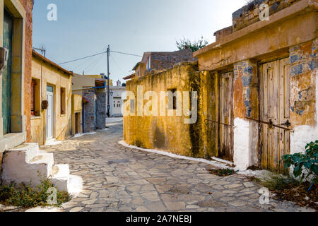 Schmale Straße mit bunten Häusern aus Stein im alten Dorf von Pano Elounda, Kreta, Griechenland.