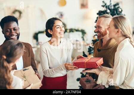 Gruppe von eleganten jungen Menschen den Austausch von Geschenken und freundlich lächelnd während der Weihnachtsfeier, kopieren Raum Stockfoto