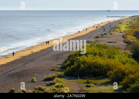 Spaziergänger, die am Strand von Dunwich, Suffolk, Großbritannien, spazieren gehen. Naturschutzgebiet Minsmere auf der rechten Seite. Stockfoto