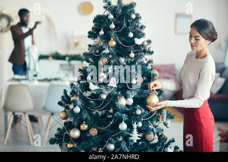 Hohen winkel Porträt des modernen Paar Vorbereitungen für die Party zu Hause, auf junge Frau schmücken Weihnachtsbaum im Vordergrund, kopieren Raum konzentrieren Stockfoto