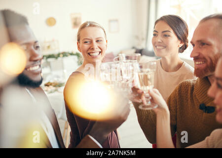 Elegante Gruppe von Freunden Gläser heben beim Feiern an Weihnachten party, konzentrieren sich auf zwei Frauen freundlich lächelnd Stockfoto