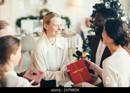 Hohen winkel Portrait von eleganten jungen Menschen den Austausch von Geschenken und glücklich lachend während der Weihnachtsfeier, kopieren Raum Stockfoto