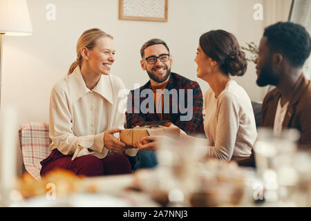 Gruppe von eleganten Erwachsenen Austausch präsentiert auf Weihnachten, auf die schöne blonde Frau lächelnd glücklich Holding Geschenkbox Fokus Stockfoto