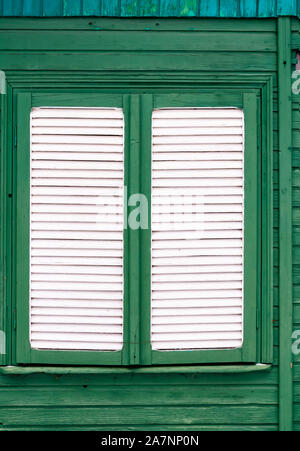 Full Frame geschossen von Verschluss der alten weißen Holz Fenster auf grüne Gebäude aus Holz Stockfoto