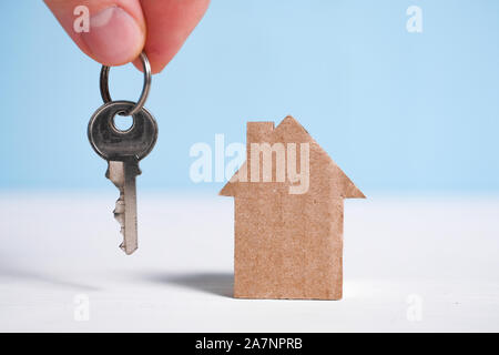 Abstrakte Pappe Haus neben eine Hand mit einem Haus. Das Konzept für den Kauf einer neuen Heimat. Close Up. Stockfoto