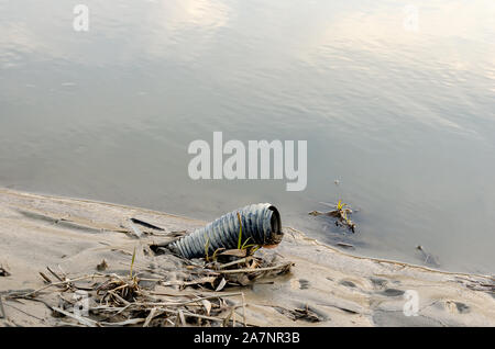 Gebrochene Kunststoff Akkordeon Schlauch am Ufer eines Flusses aufgegeben. Stockfoto